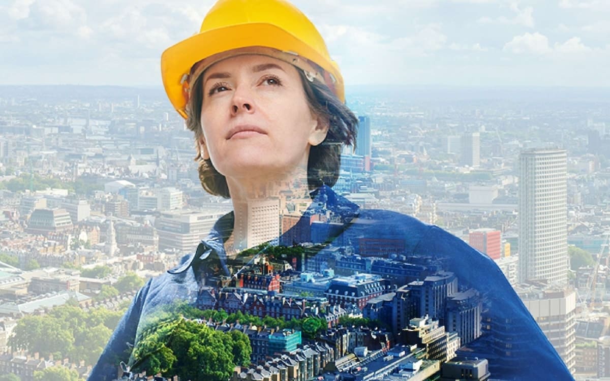 Double exposure image of female in a yellow hard hat with a cityscape behind her.