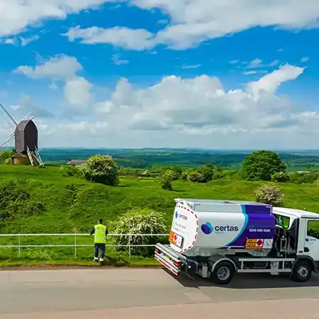 Certas Energy delivery truck parked in the British countryside with a windmill in the background.