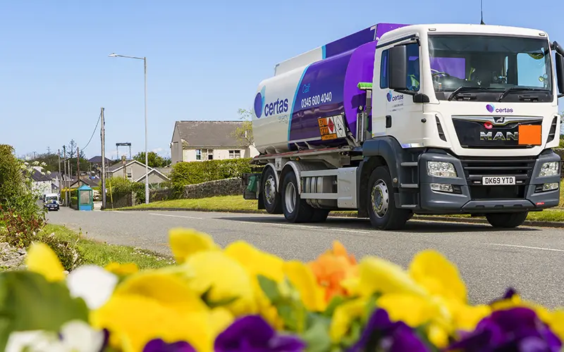 Certas Energy branded truck with yellow flowers in foreground.