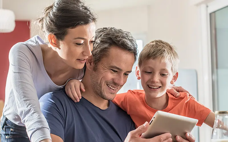 Woman, man and small boy looking at ipad and smiling.