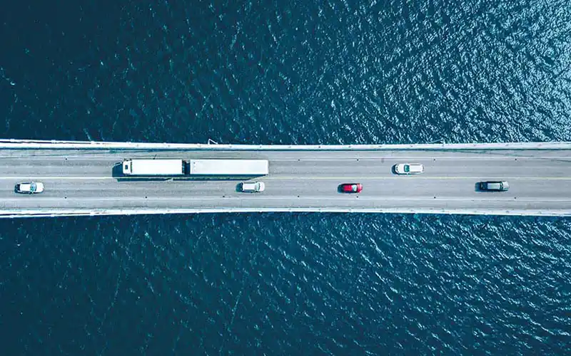 vehicles driving across a sea bridge