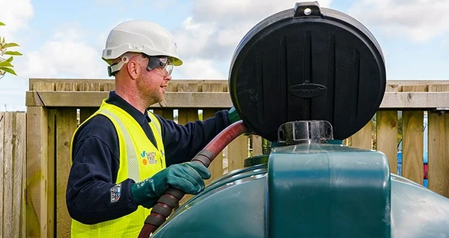 Certas Energy delivery driver putting fuel in a fuel tank.