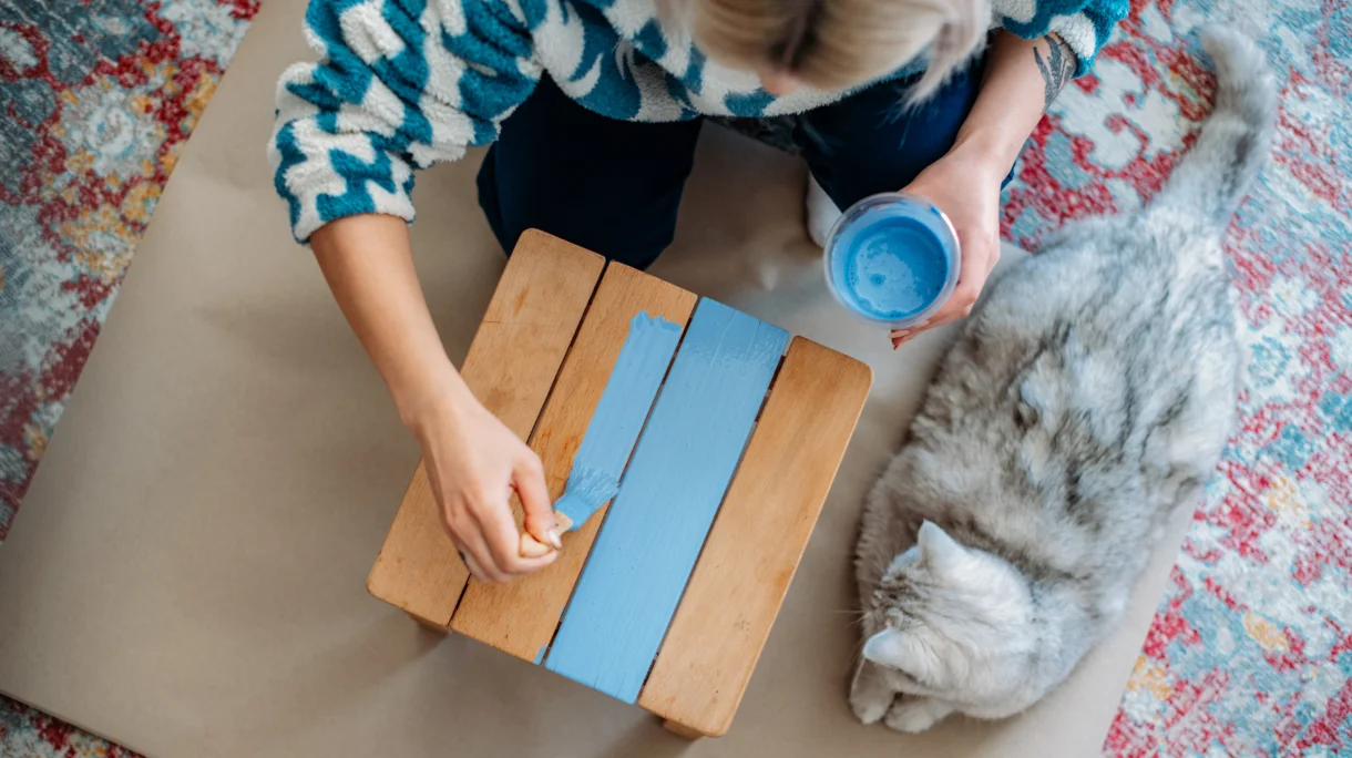 Woman painting side table blue during upcycling project