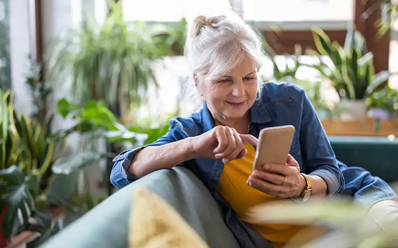 Lady sat on sofa looking at mobile phone.
