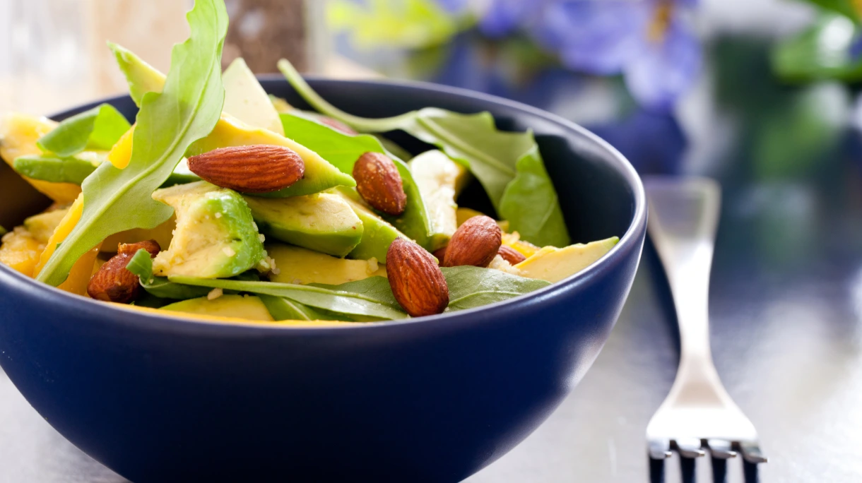 Salad bowl including leaves, avocado and almonds for budget conscious healthy snacking.