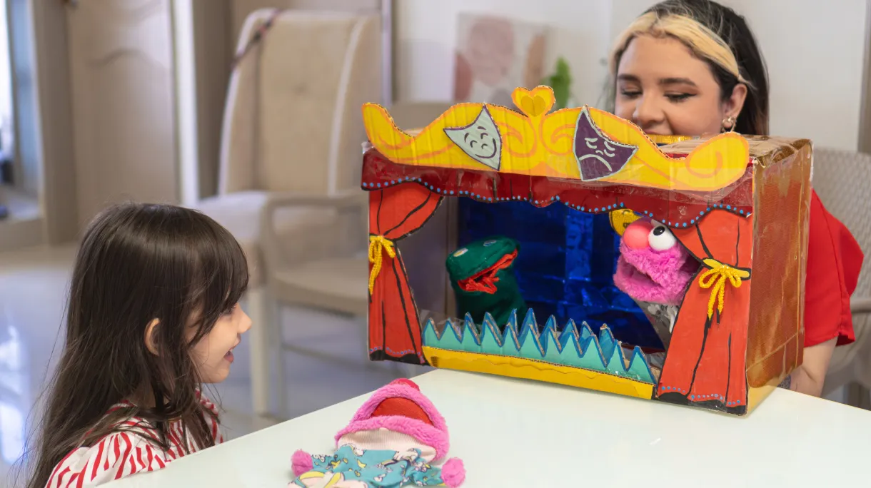 Mum and child performing sock puppet show with DIY stage